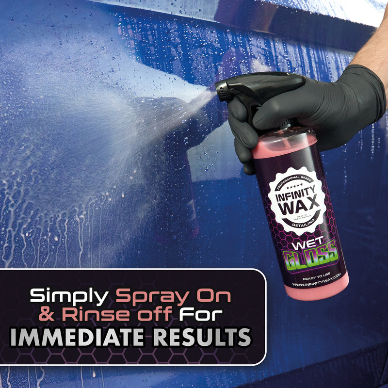 Person applying Infinity Wax spray to a car's surface with promotional text.